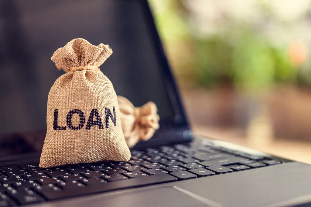 a personal loan money bag resting on a laptop keyboard with a blurred background