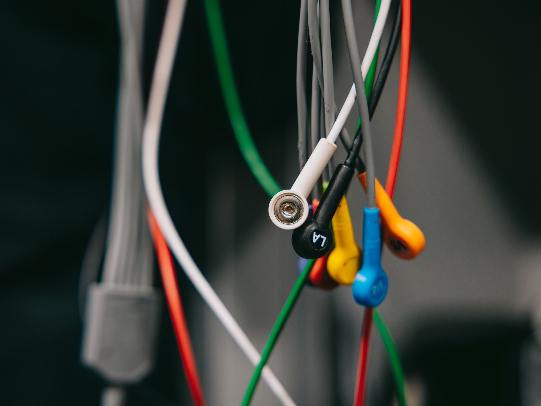 Close-up of multicolored medical ECG electrode cables hanging together.