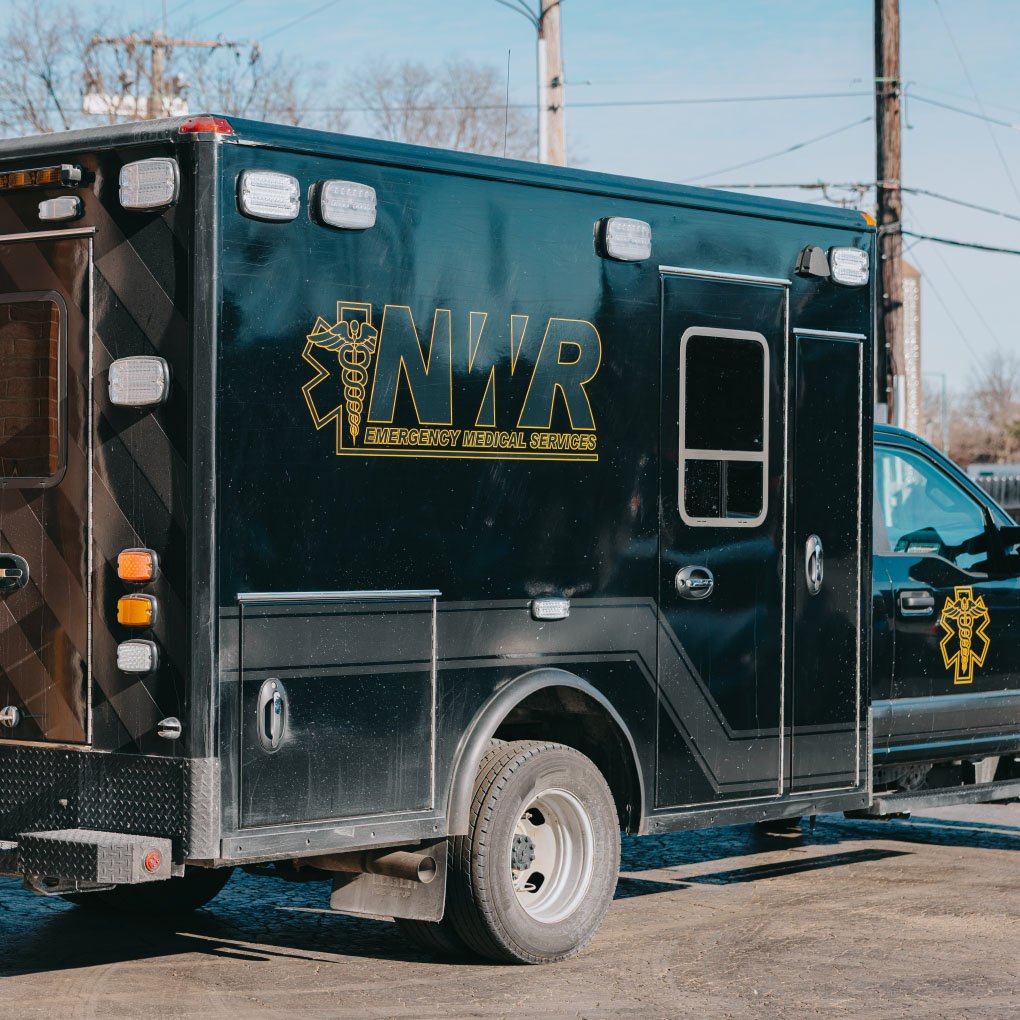 Black emergency medical services vehicle with NWR logo parked outdoors on a sunny day.
