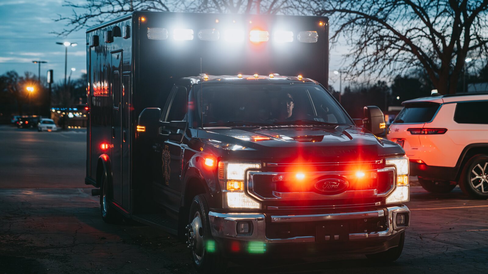 Northwest Rescue ambulance staged at dusk with emergency lights active, providing event EMS standby coverage for organizers in Illinois.