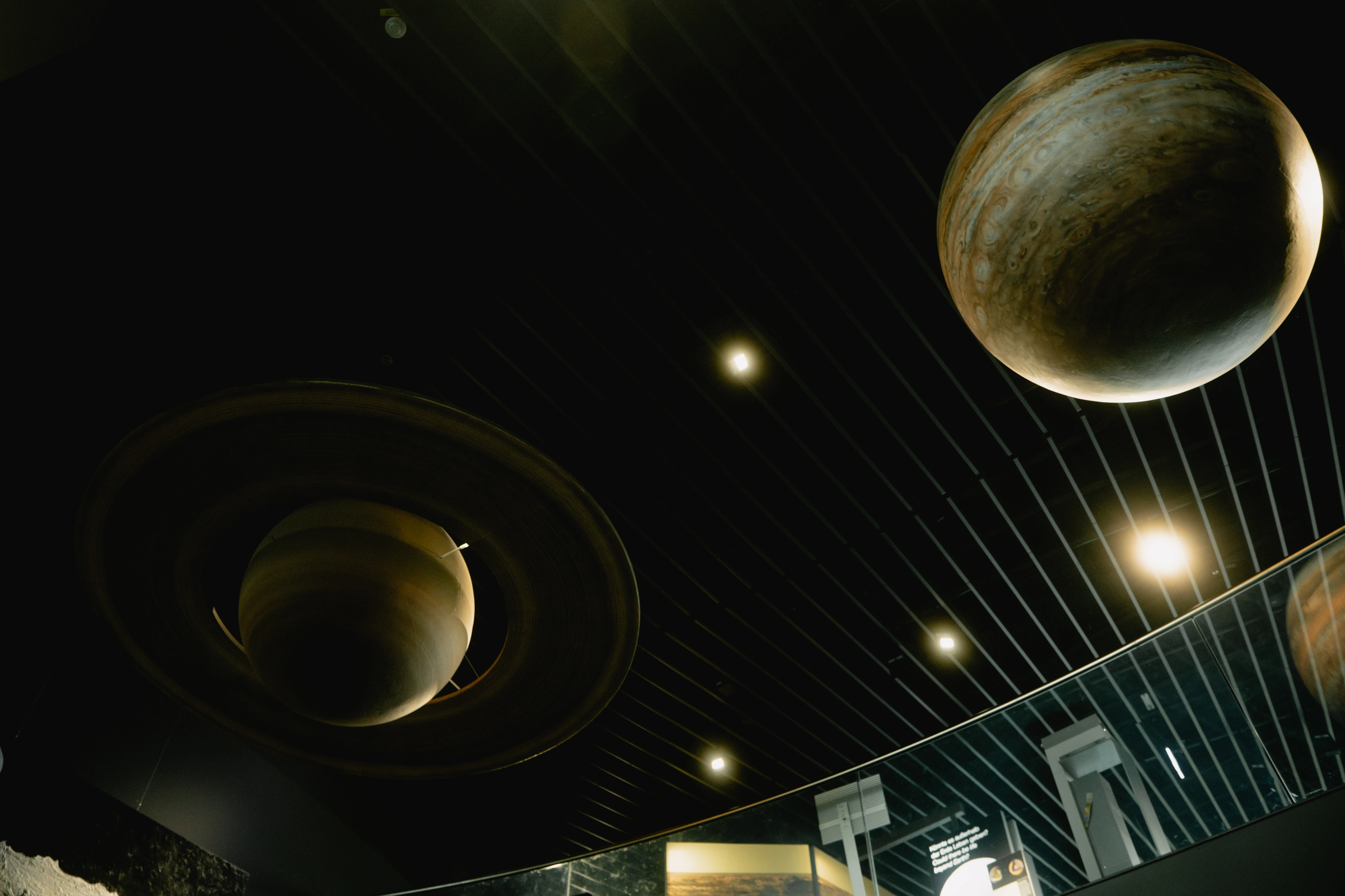 Indoor exhibit of planet models, including Saturn with rings and Jupiter hanging from the ceiling at ESO Supernova Planetarium.