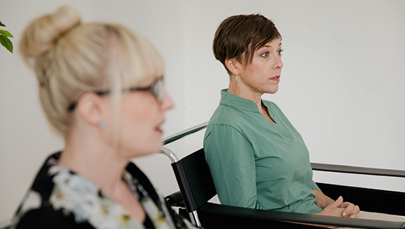 Zwei Frauen sitzen einander gegenüber und sprechen im Rahmen eines Mediationsgesprächs