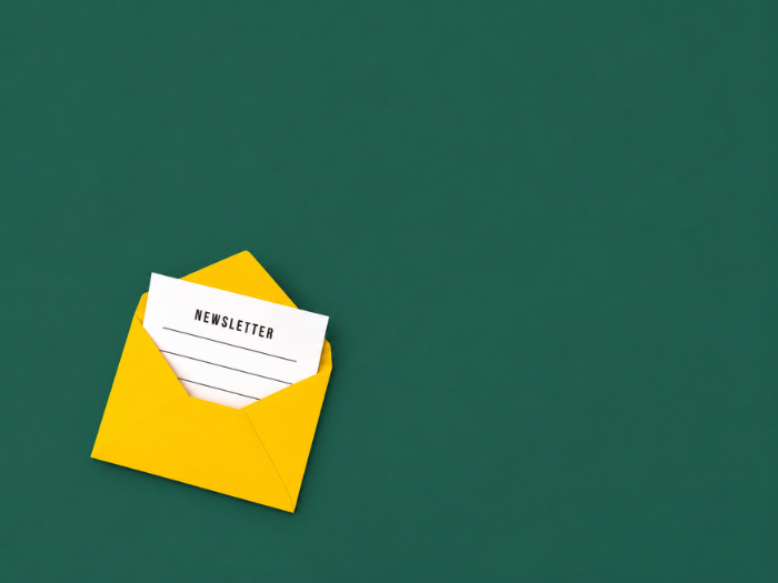 Gelber Umschlag mit einem Newsletter-Zettel vor einem dunkelgrünen Hintergrund