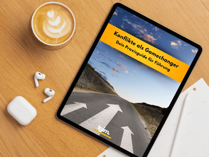 Vorschau des tgim-Konflikte-e-Books auf einem Tablet, das auf dem Tisch neben einem Kaffee liegt.