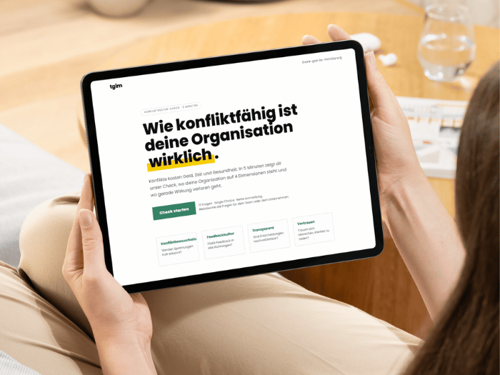 Eine Person hält ein Tablet mit dem tgim Konfliktescore in den Händen, der die Konfliktfähigkeit einer Organisation überprüft.