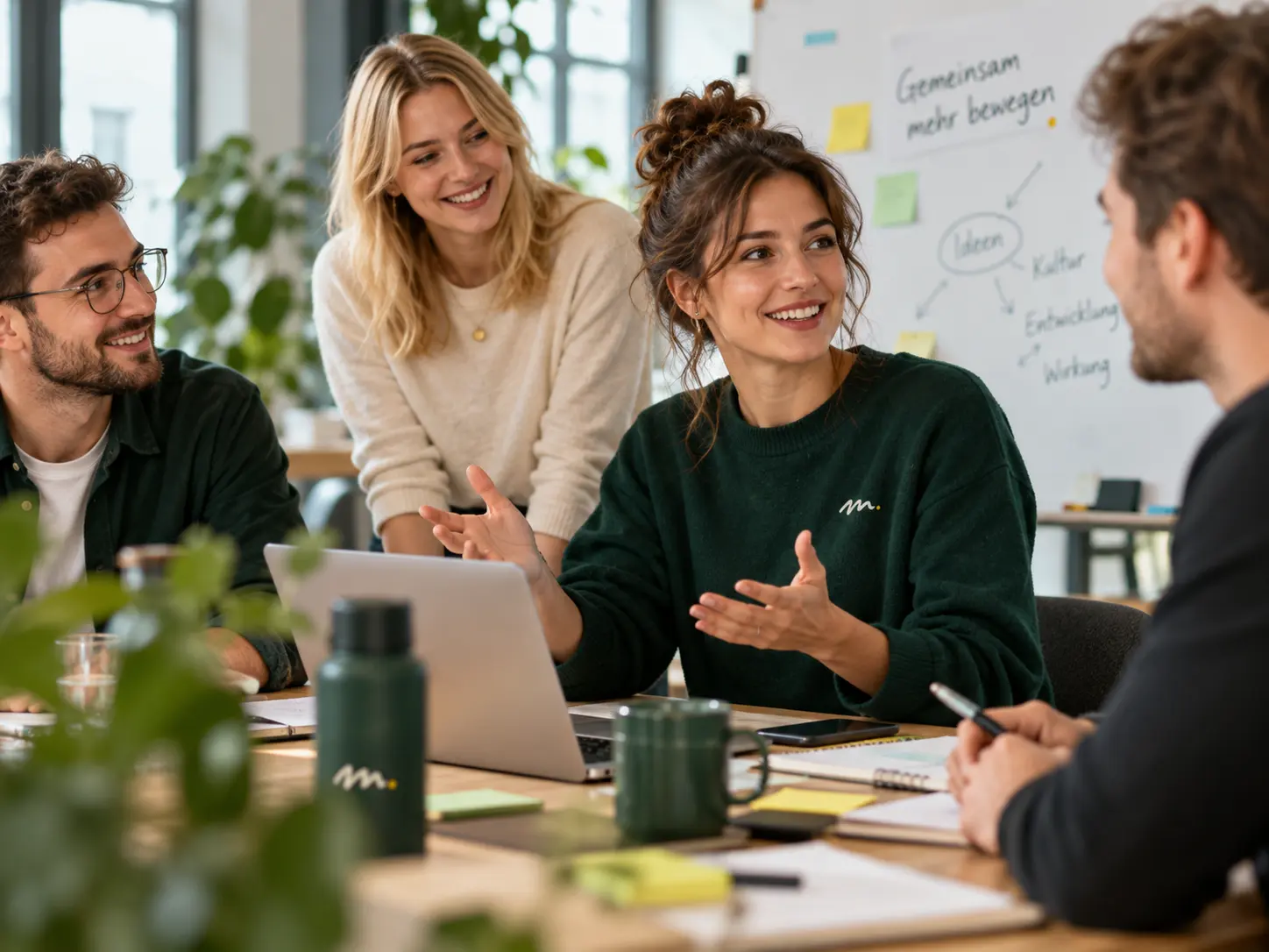 Mitarbeitende arbeiten in einem offenen Teamgespräch zusammen, bringen Ideen ein und begegnen sich in einer freundlichen, aktiven Arbeitsatmosphäre.