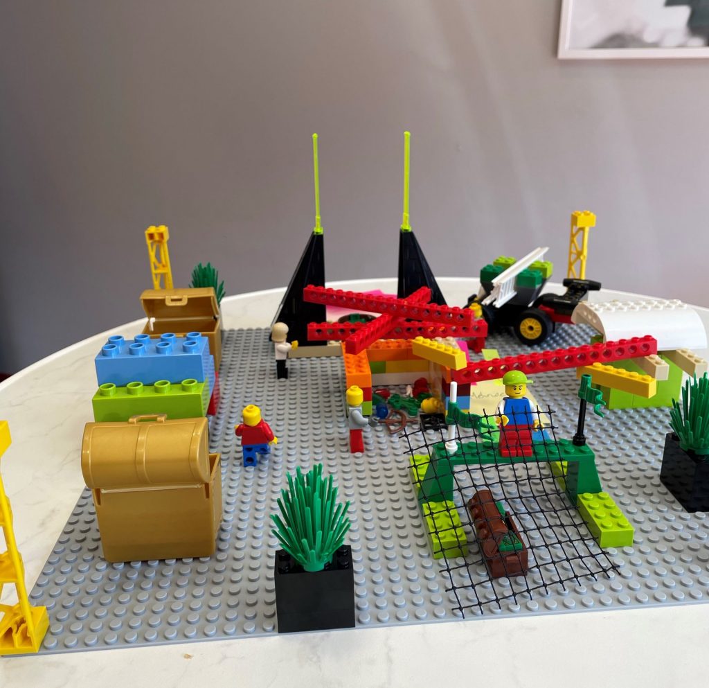 LEGO Serious Play Modell mit Figuren, Bausteinen und Symbolen zur Darstellung von Zusammenarbeit, Strukturen und Veränderungsprozessen.