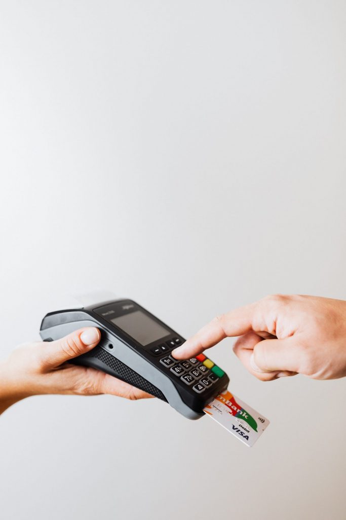 Person bezahlt mit Karte an einem mobilen Kartenterminal, während eine andere Person den Zahlungsvorgang bestätigt.