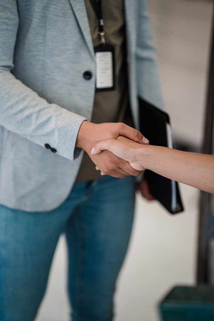 Zwei Personen geben sich zur Begrüßung oder nach einer erfolgreichen Vereinbarung die Hand.