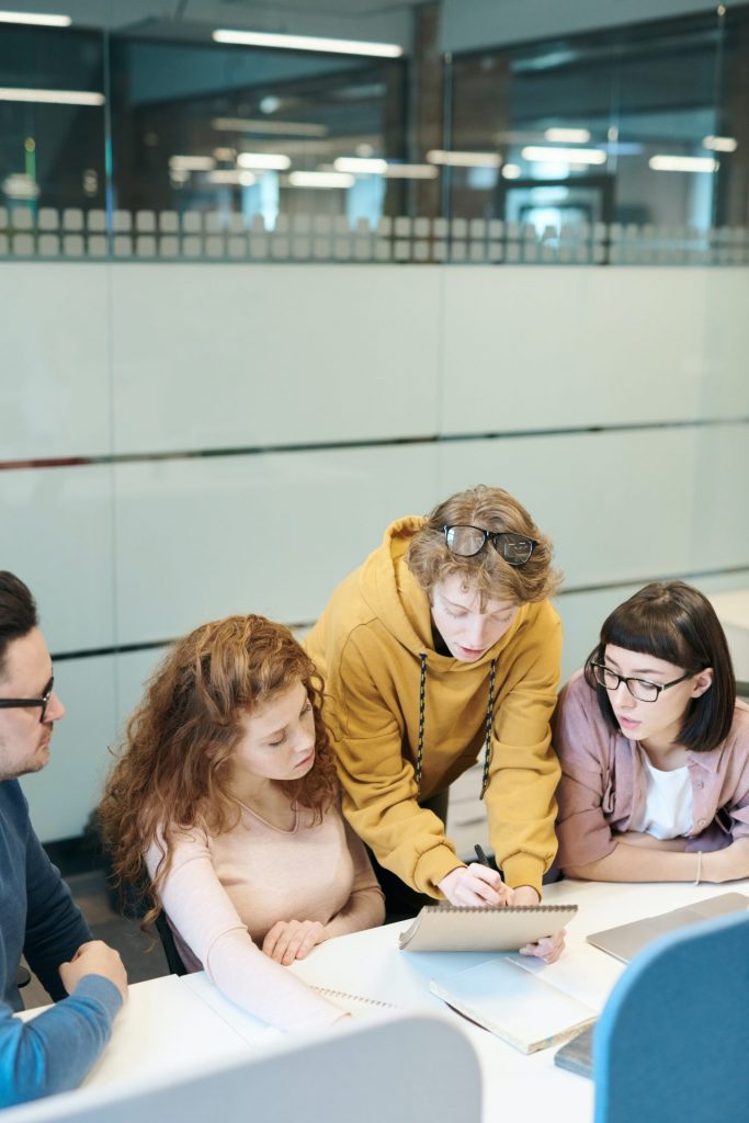 Junges Team sitzt gemeinsam an einem Tisch und arbeitet konzentriert an Notizen für ein Projekt.