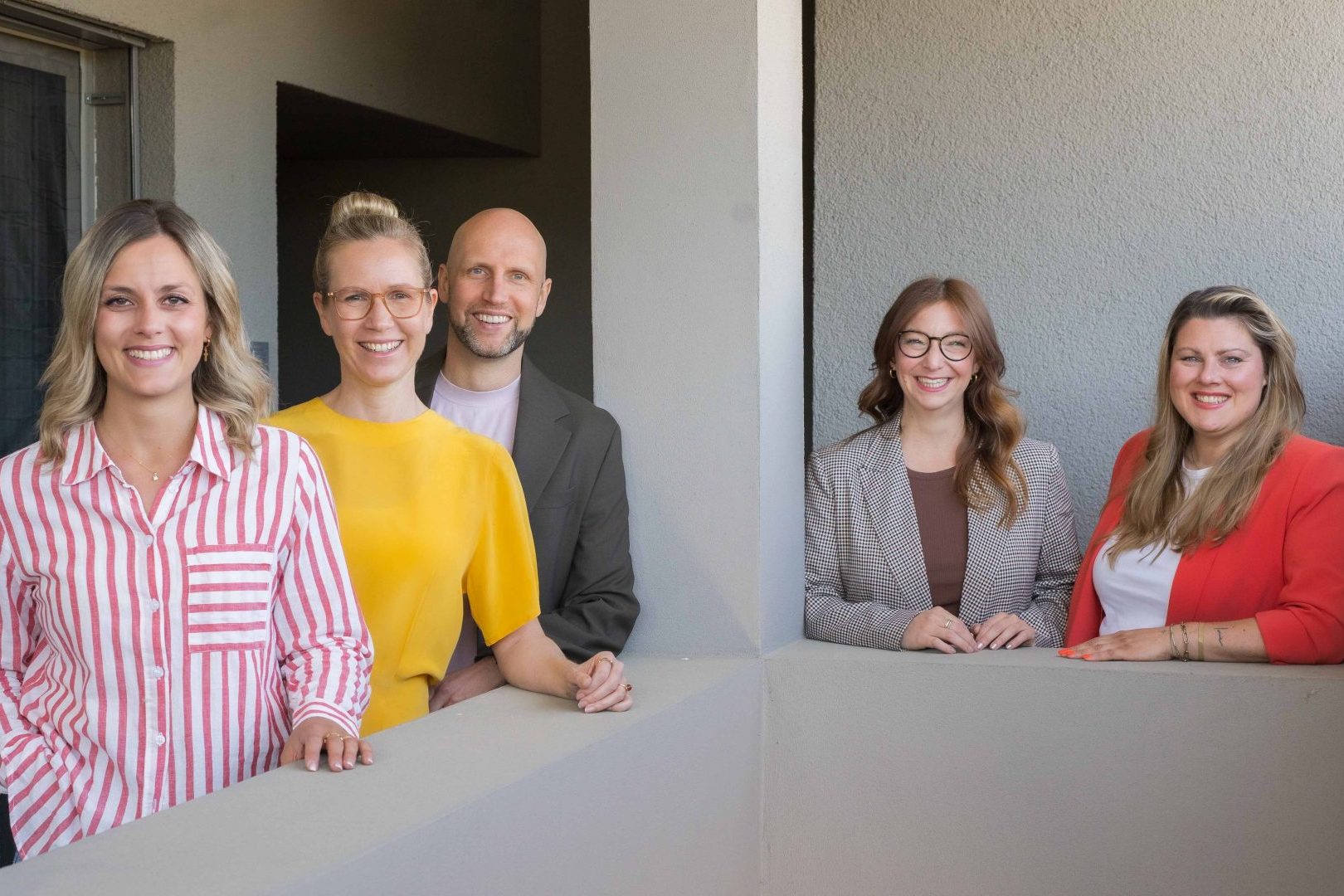 tgim-Team lächelt gemeinsam in die Kamera.