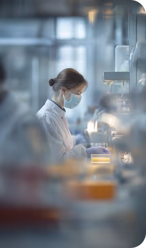 Investigadora con bata y mascarilla trabajando en un laboratorio con equipo científico.