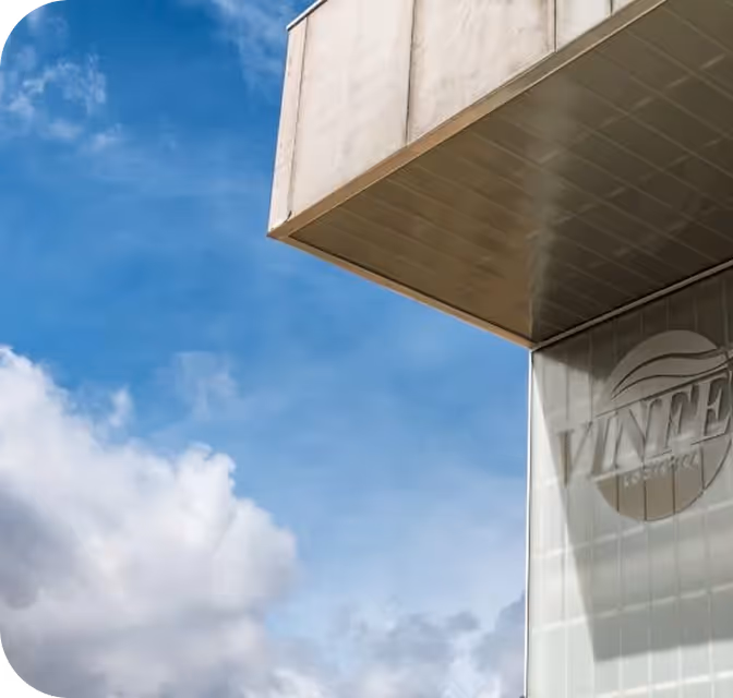 Parte superior de un edificio con cielo azul y nubes, mostrando un logotipo circular con la palabra 'VINTAGE'.