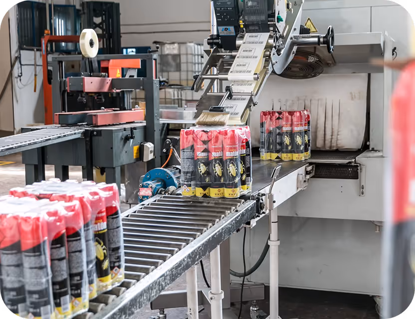 Línea de producción con máquina etiquetadora aplicando etiquetas a paquetes de latas en una fábrica.