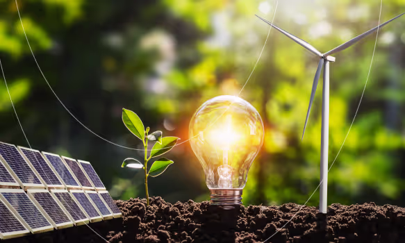 Glowing light bulb in soil between a small plant, solar panels, and a wind turbine against a green blurred background symbolizing renewable energy.