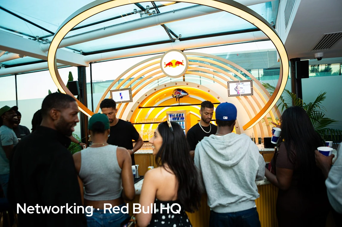 People socializing at a Red Bull branded bar under glowing circular light arches indoors.