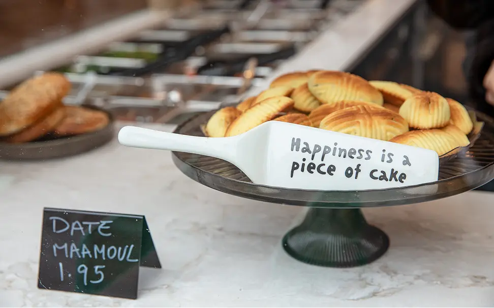Plate of date maamoul cookies with a sign that reads 'Happiness is a piece of cake'.