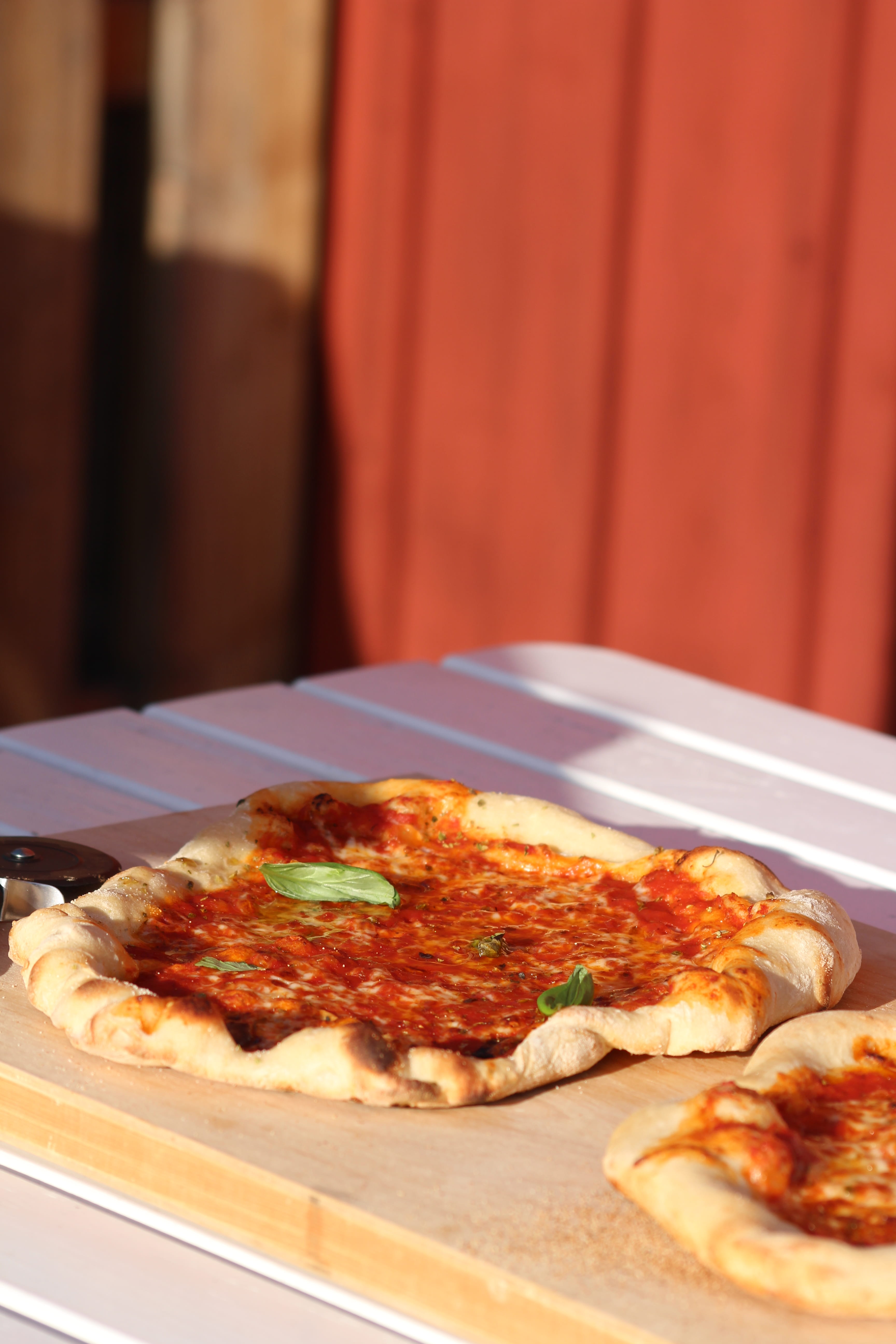 Close-up of a glass of clear liquid with a sprig of herbs, surrounded by blurred glasses on a table, creating a cozy dining atmosphere.