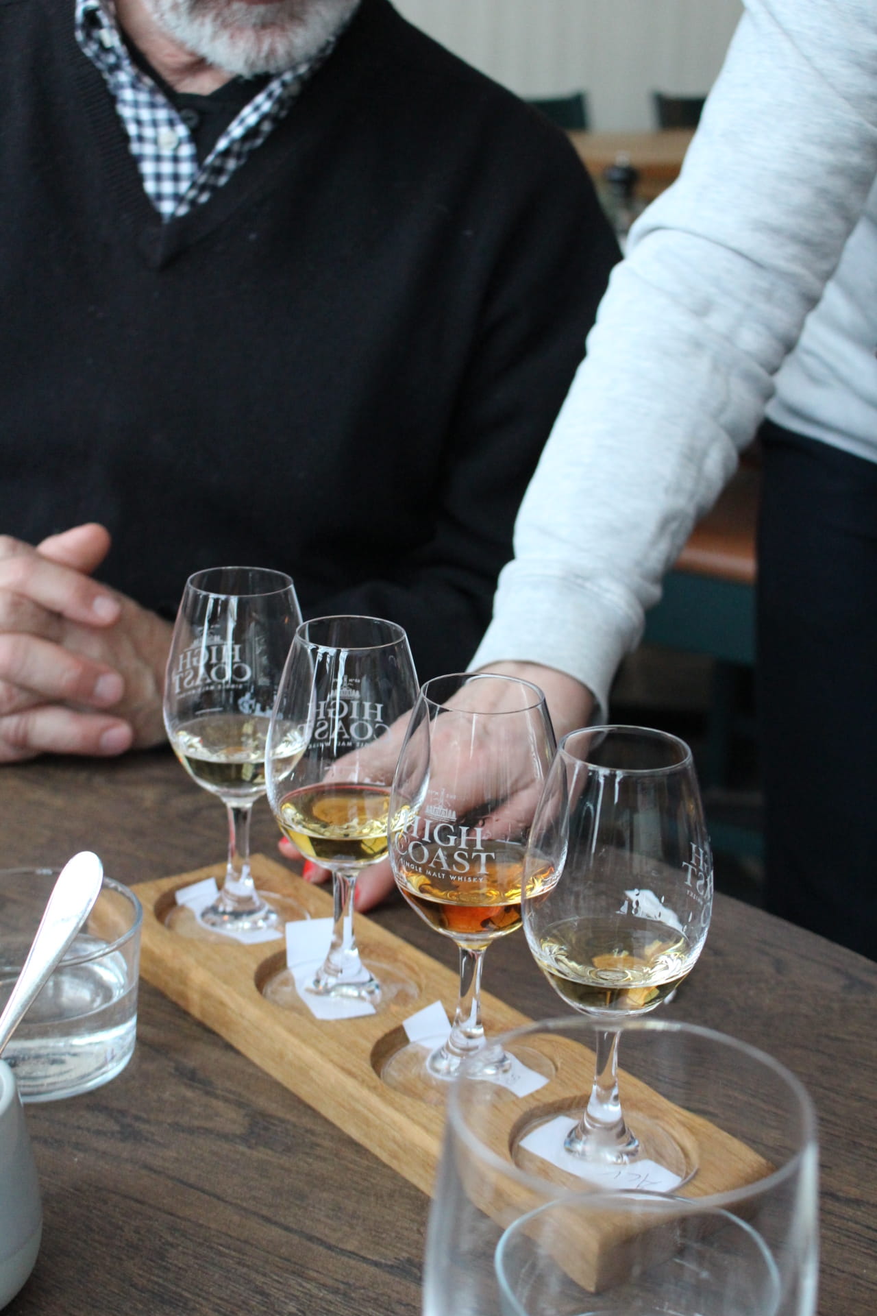 A small, dark gray bird perched on a branch, surrounded by lush green foliage, softly blending into its natural habitat.