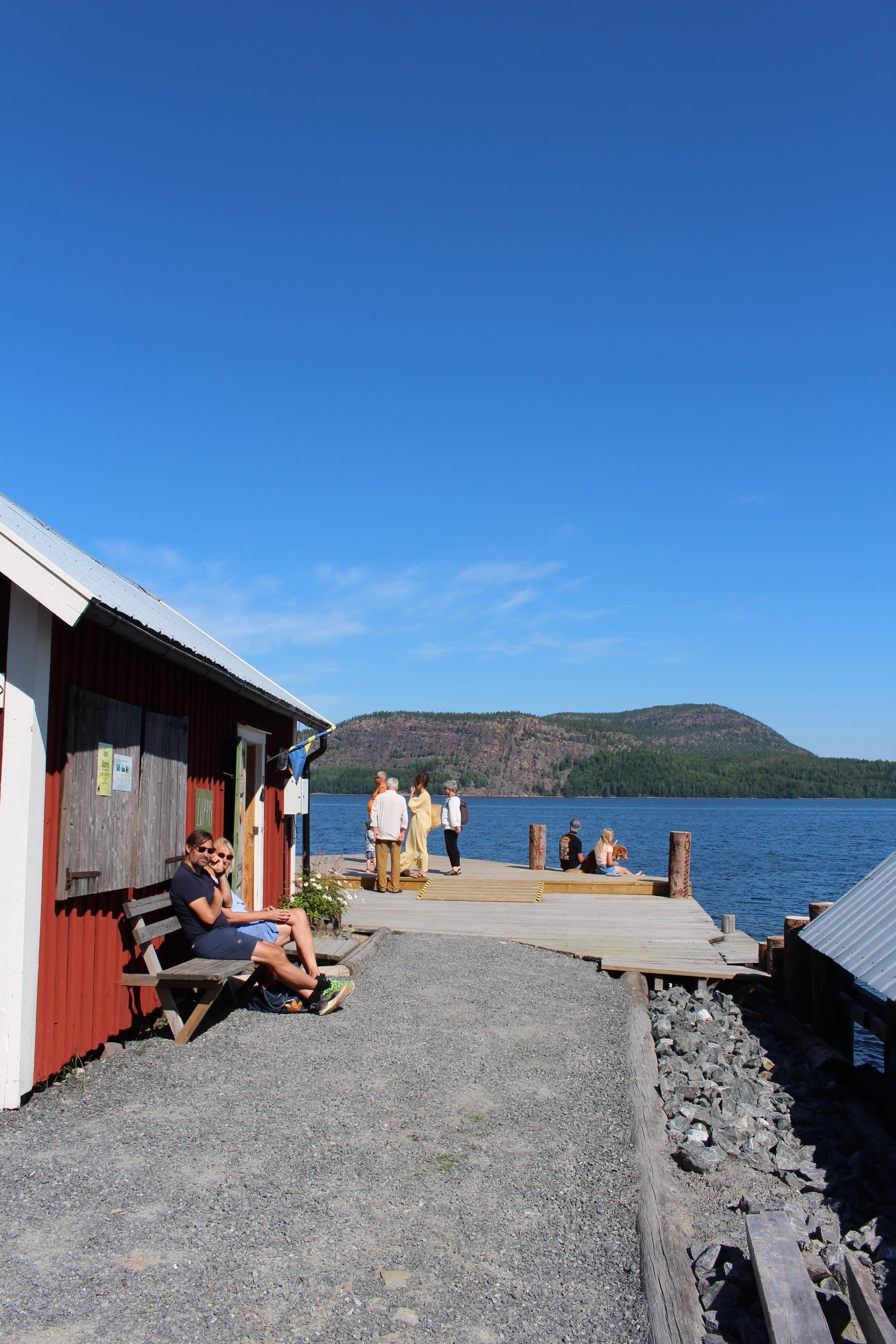 Aerial view of three kayakers in green and yellow kayaks paddling on dark blue water, creating gentle ripples around them.