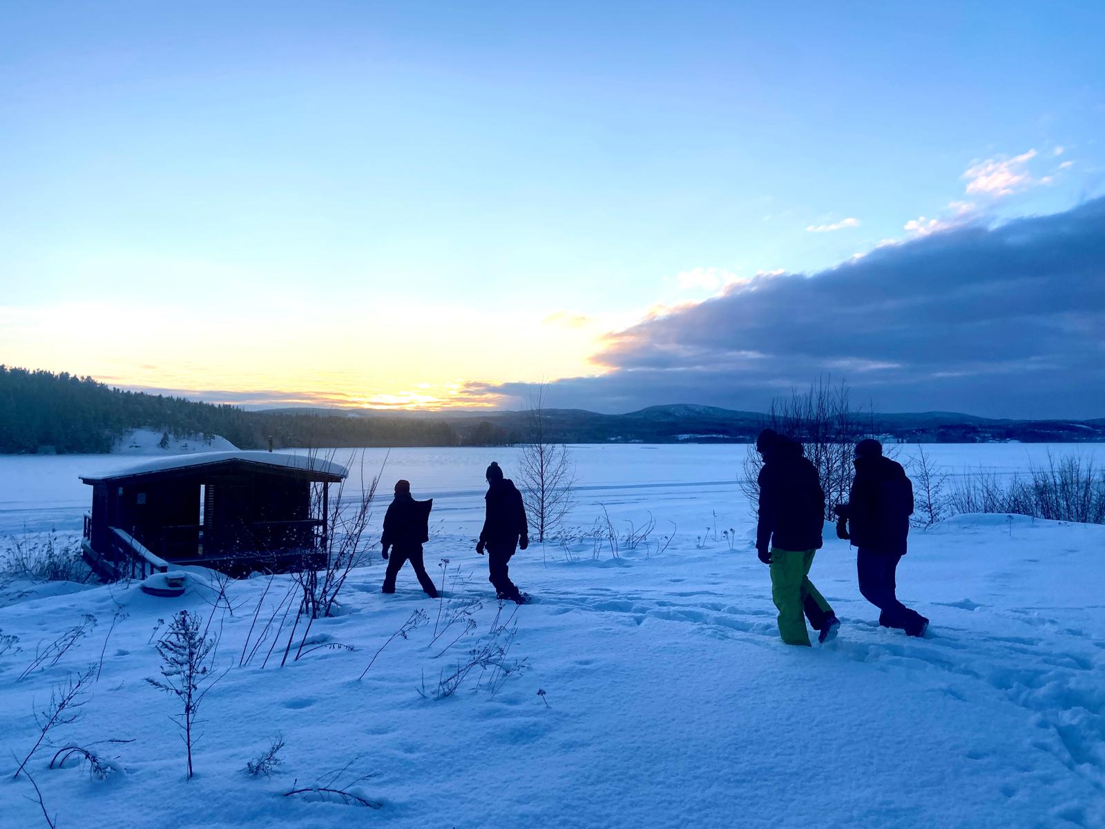 Kayakers paddle in the tranquil waters near a large, eroded rock formation, surrounded by lush greenery and cliffs.