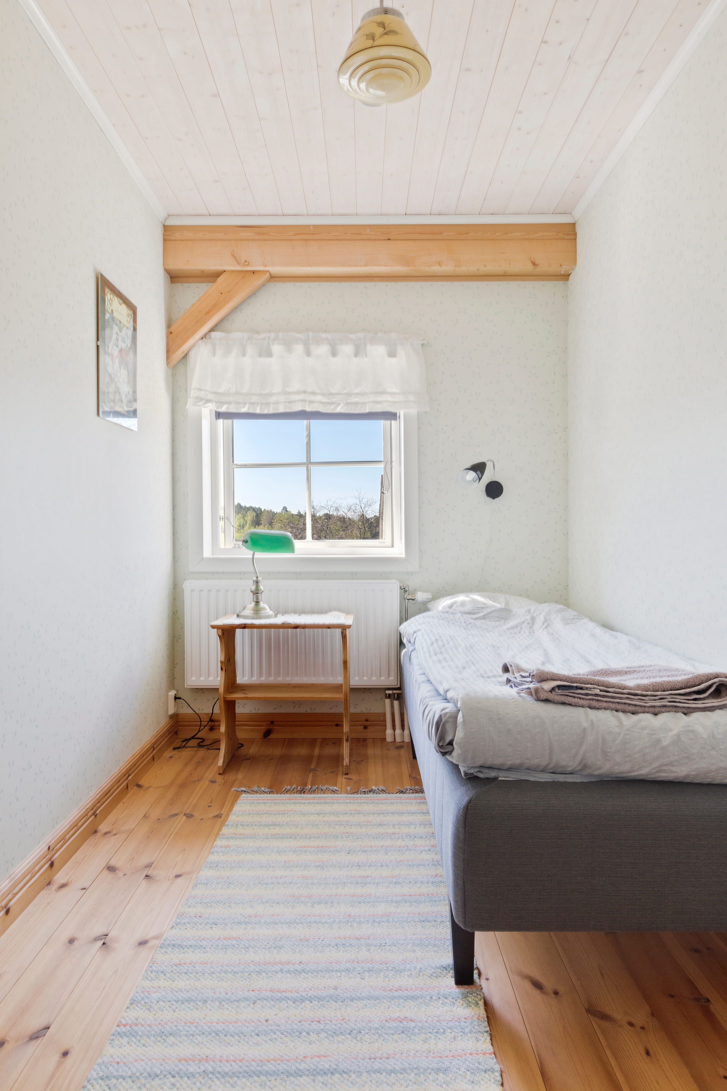 A modern blue house nestled among lush green trees and hills under a cloudy sky, surrounded by tranquil nature.