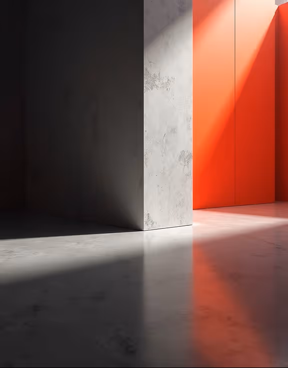 Concrete corner wall casting shadows on polished floor with sunlight illuminating a vibrant red wall in the background.