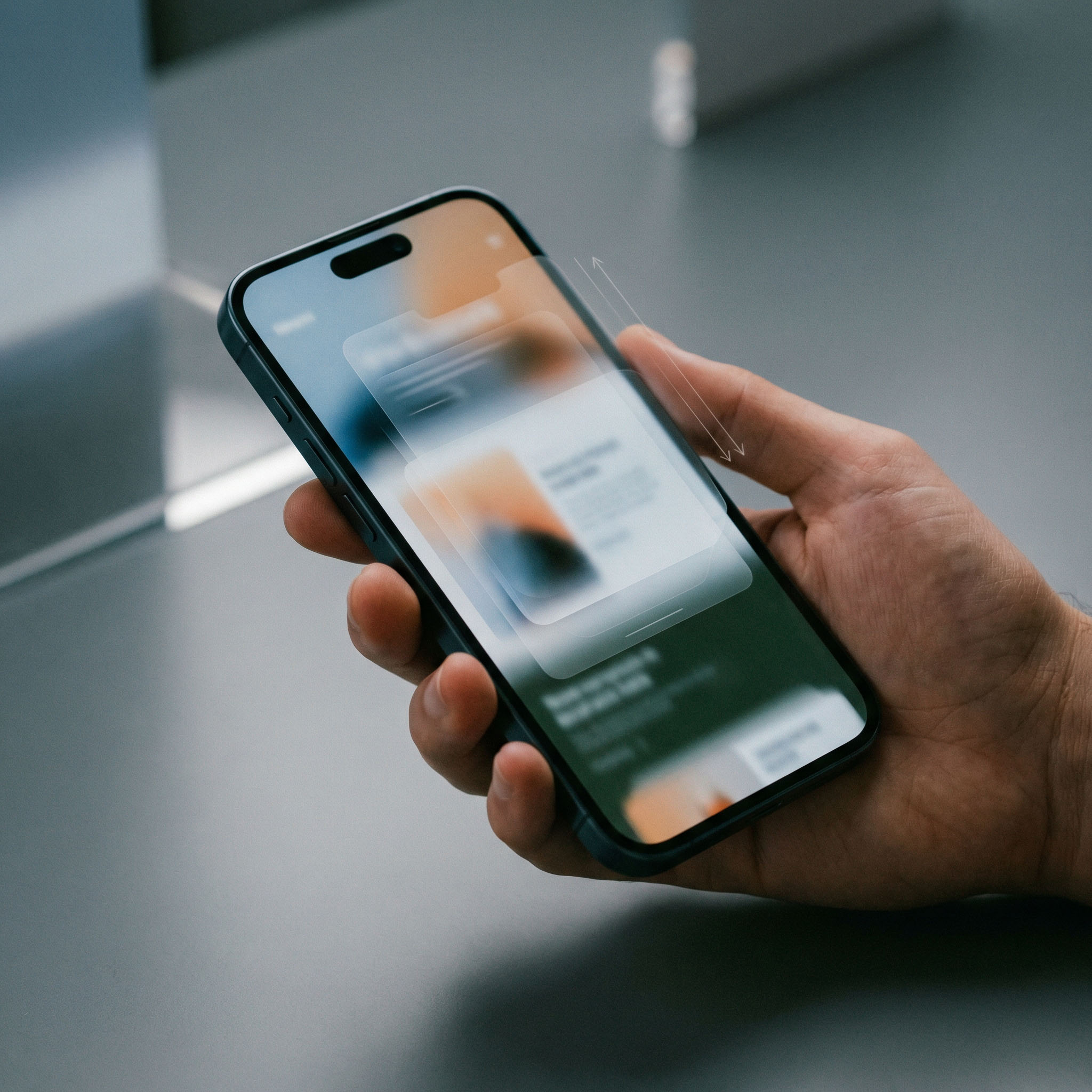 Hand holding a smartphone displaying a blurred screen with app interface and vertical swipe arrows.