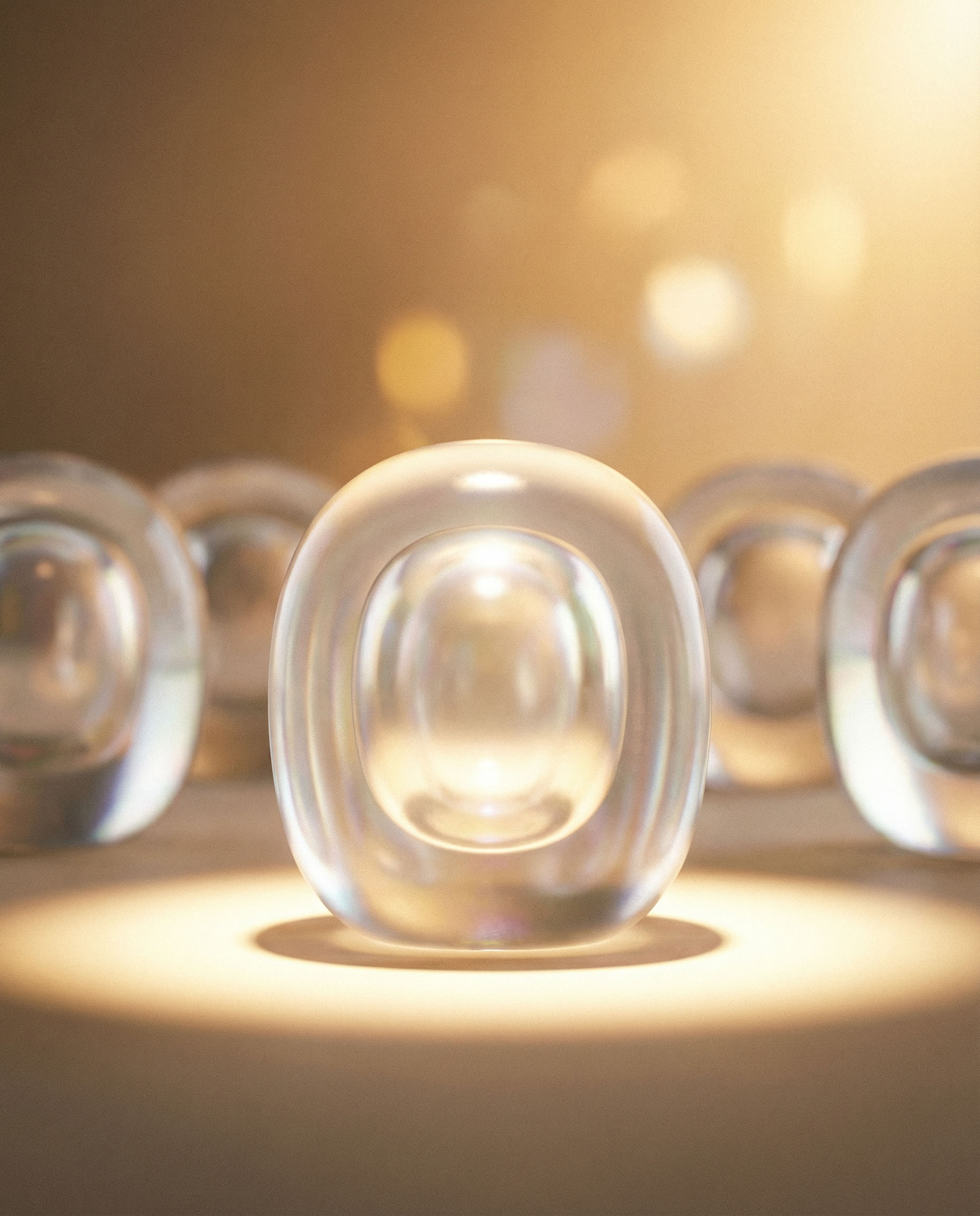 Clear glass or crystal oval-shaped objects arranged in rows with warm light and bokeh effect.