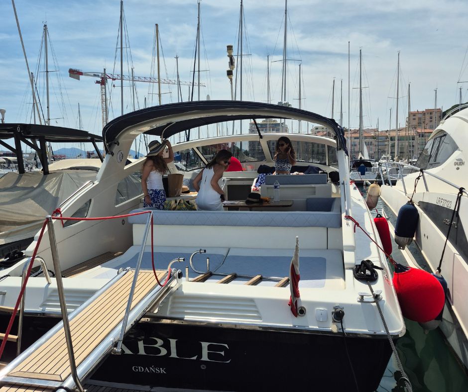 Group of men in white polo shirts and caps sailing a yacht under clear blue sky.