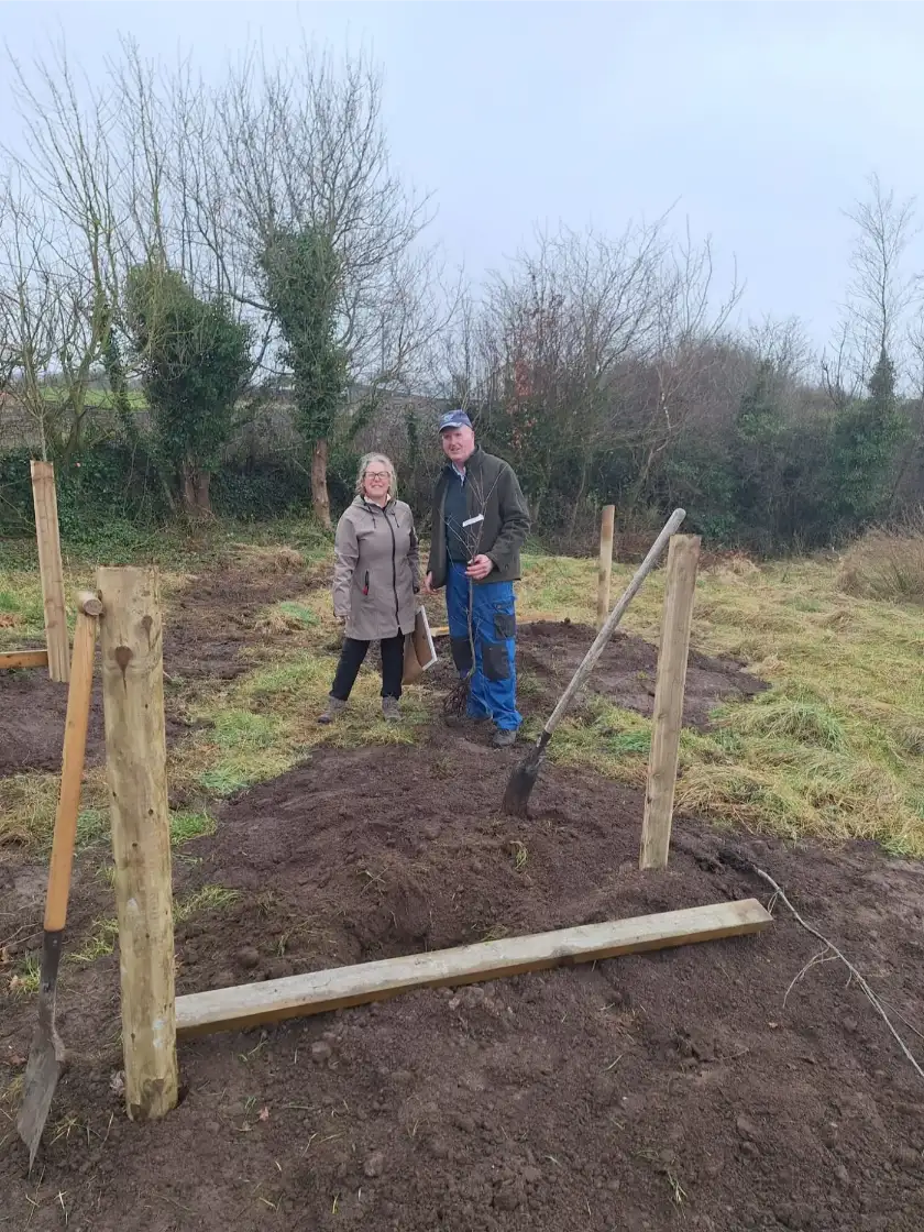 Couple digging together to prepare soil for tree planting at restoration event.