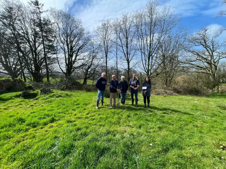 Group of volunteers planting trees across a bare landscape during restoration work.