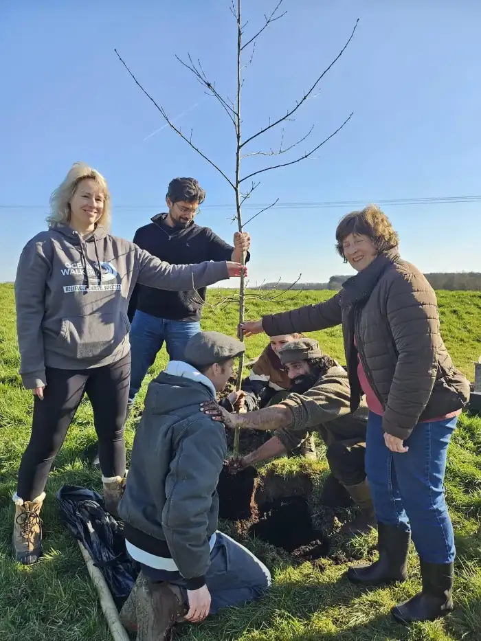 Community gathering at a group tree-planting event in the countryside.