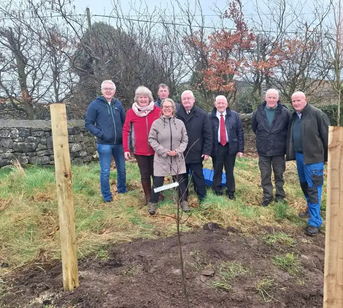 Volunteers gathered for a ceremonial tree-planting event in the countryside.