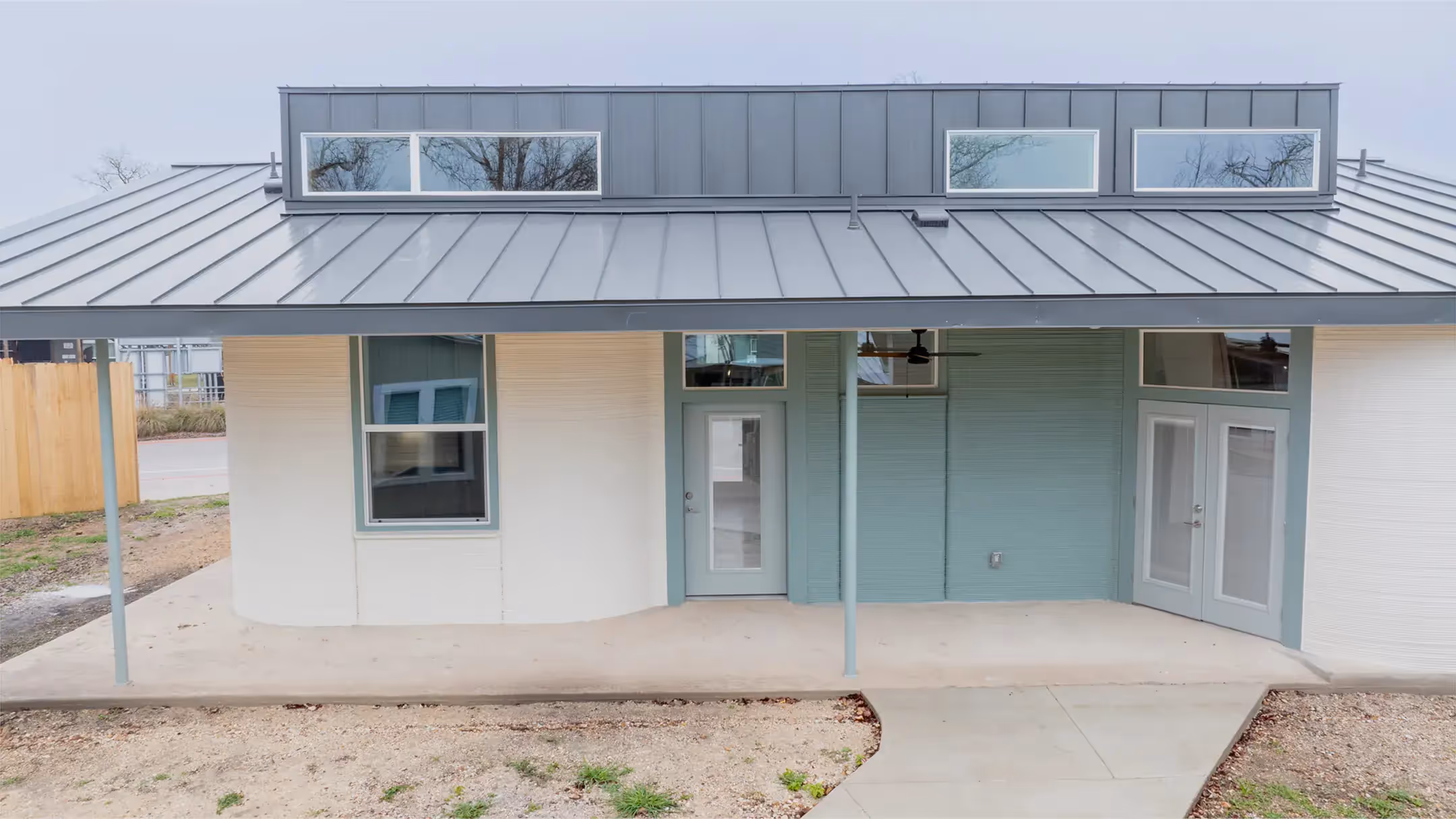Front porch of a modern home with metal roof, central glass door and right-side French doors
