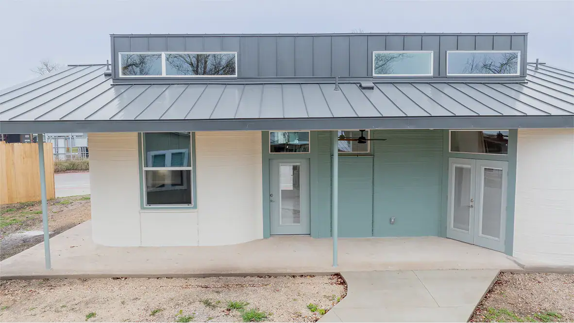 Front porch of modern home with metal roof, teal and white exterior and glass doors