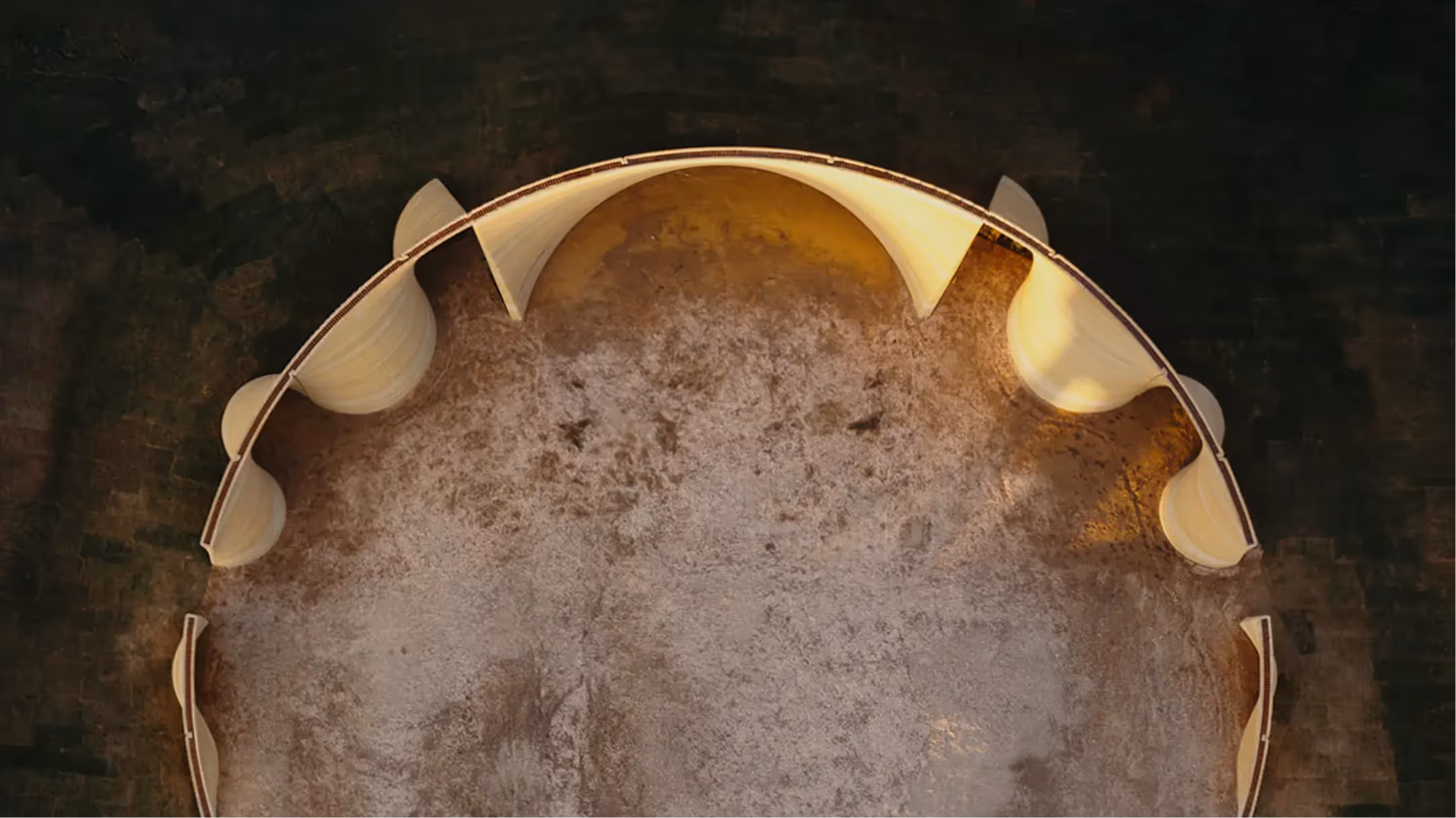 Aerial view of curved 3D-printed concrete walls forming a partial circular structure