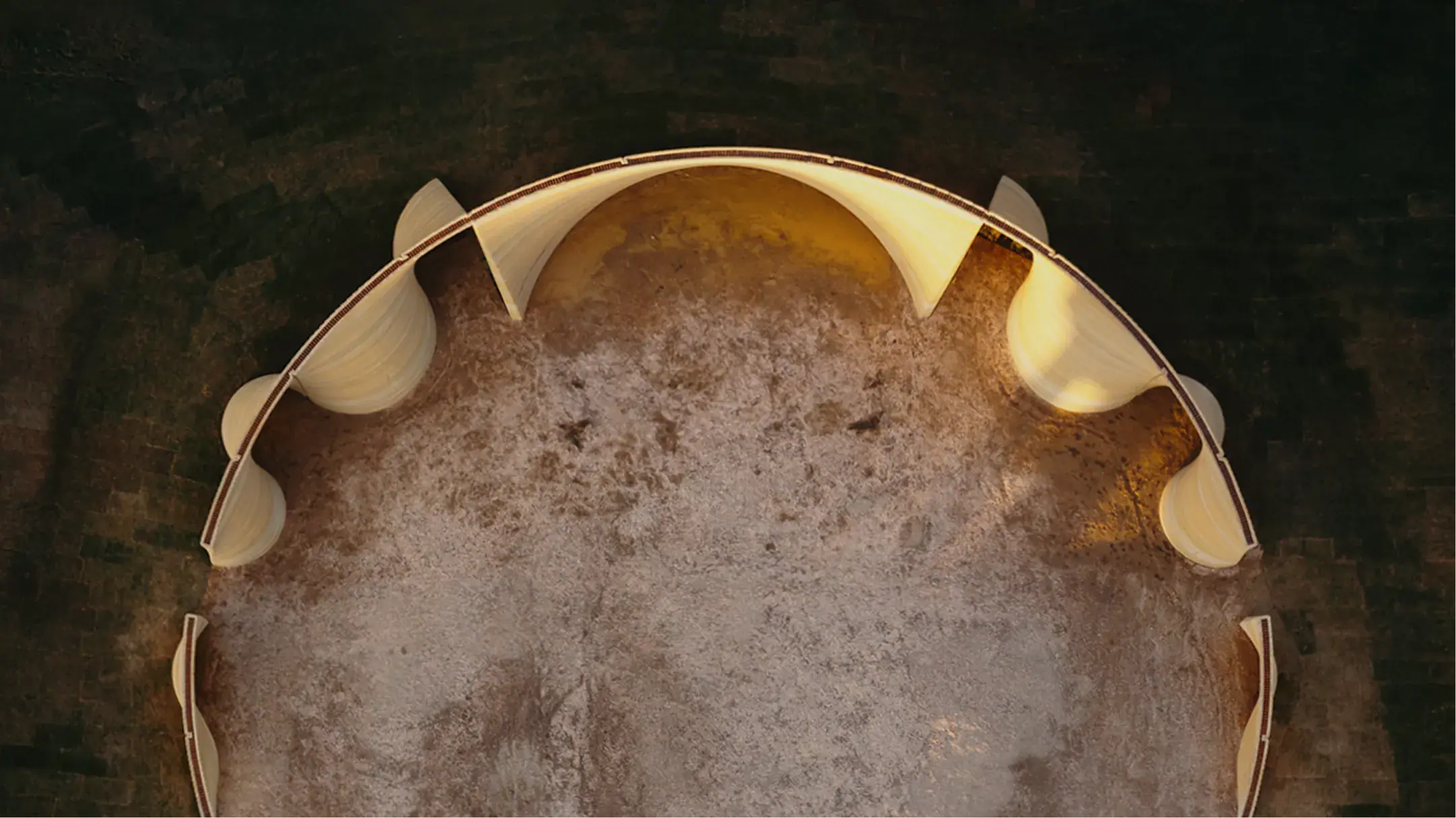 Aerial view of curved 3D-printed concrete walls forming a partial circular structure