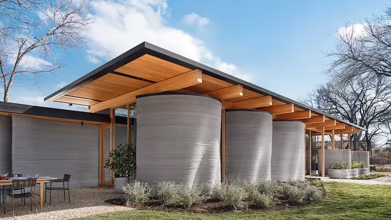 Modern home with cylindrical 3D-printed concrete walls and wood roof overhang