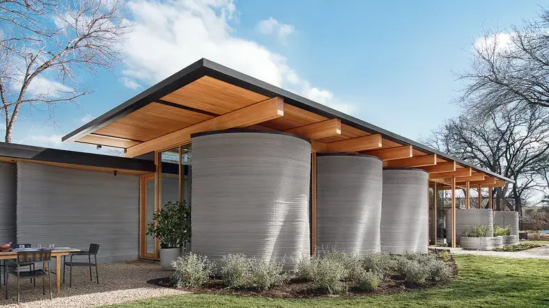 Modern home with cylindrical 3D-printed concrete walls and wood roof overhang