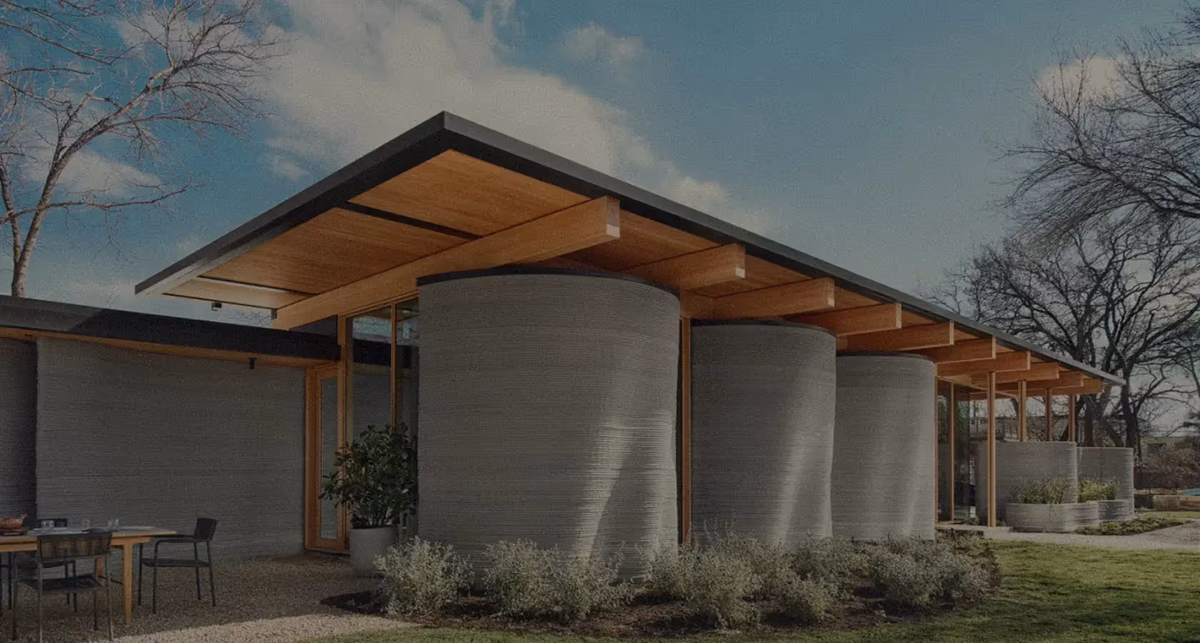 Modern home with 3D-printed cylindrical concrete walls and wood overhang