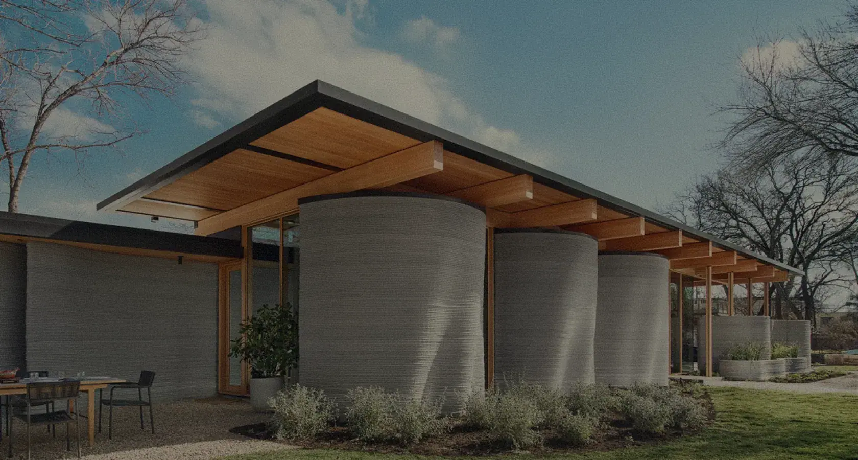 Modern home with 3D-printed cylindrical concrete walls and wood overhang
