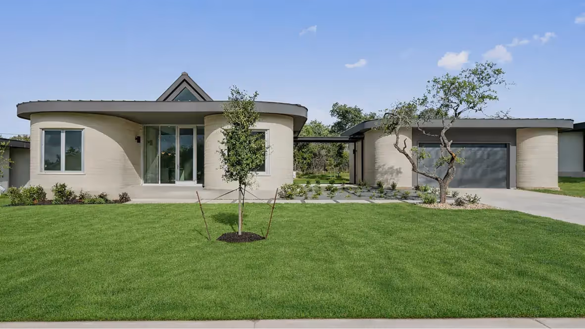 Modern single-story house with curved light exterior walls, glass entrance, garage, and green lawn