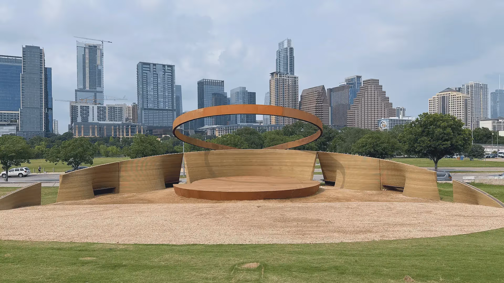 Circular stage with rust-colored ring sculpture and downtown skyline