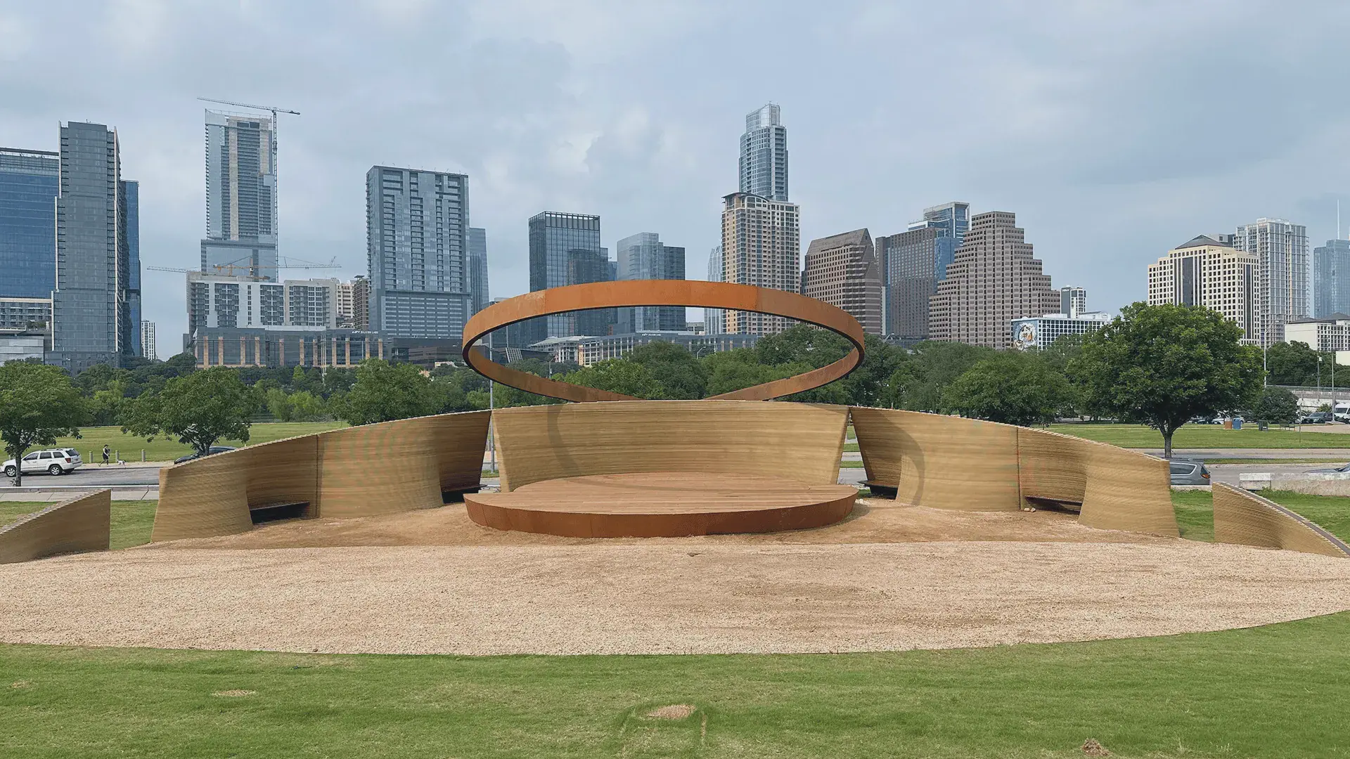 Circular stage with rust-colored ring sculpture and downtown skyline