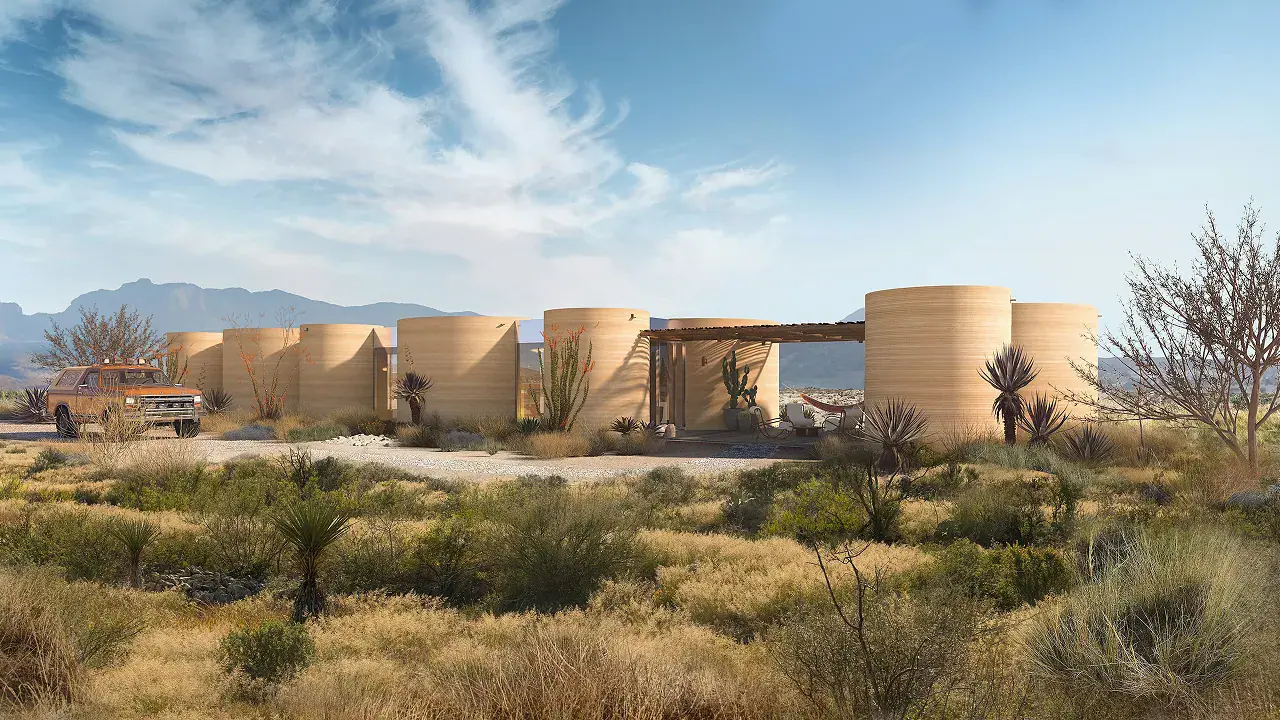 Cylindrical 3D-printed desert homes with a parked pickup truck and native desert plants