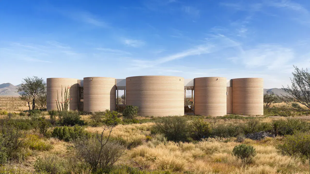 Row of cylindrical 3D-printed home modules in a desert landscape