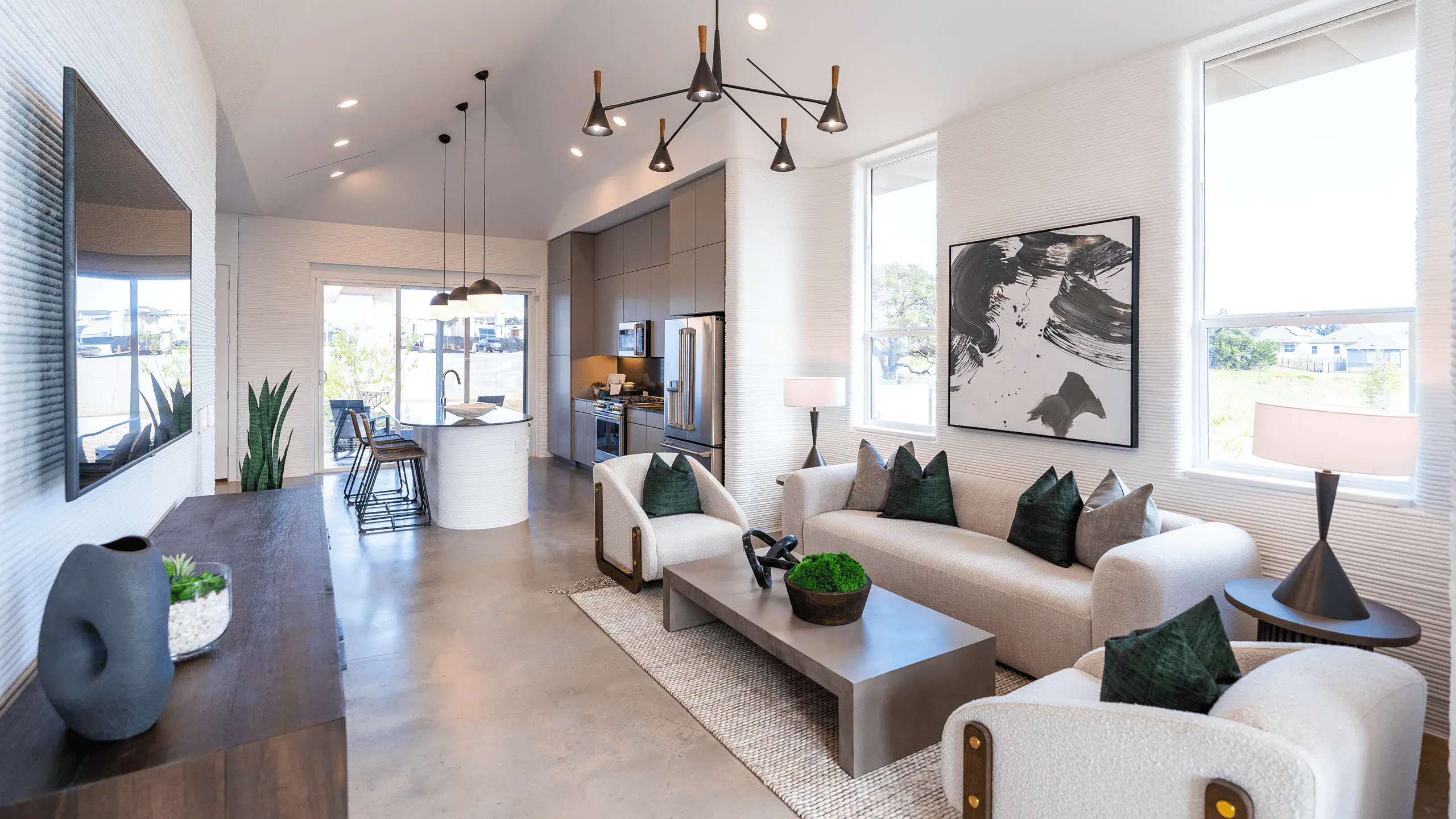 Open-plan living room and kitchen with curved island, modern sofa, and large windows
