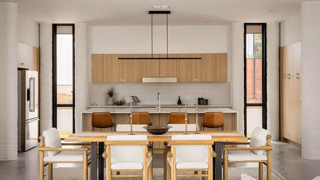 Modern kitchen and dining area with wood cabinets, island seating, and wooden dining chairs