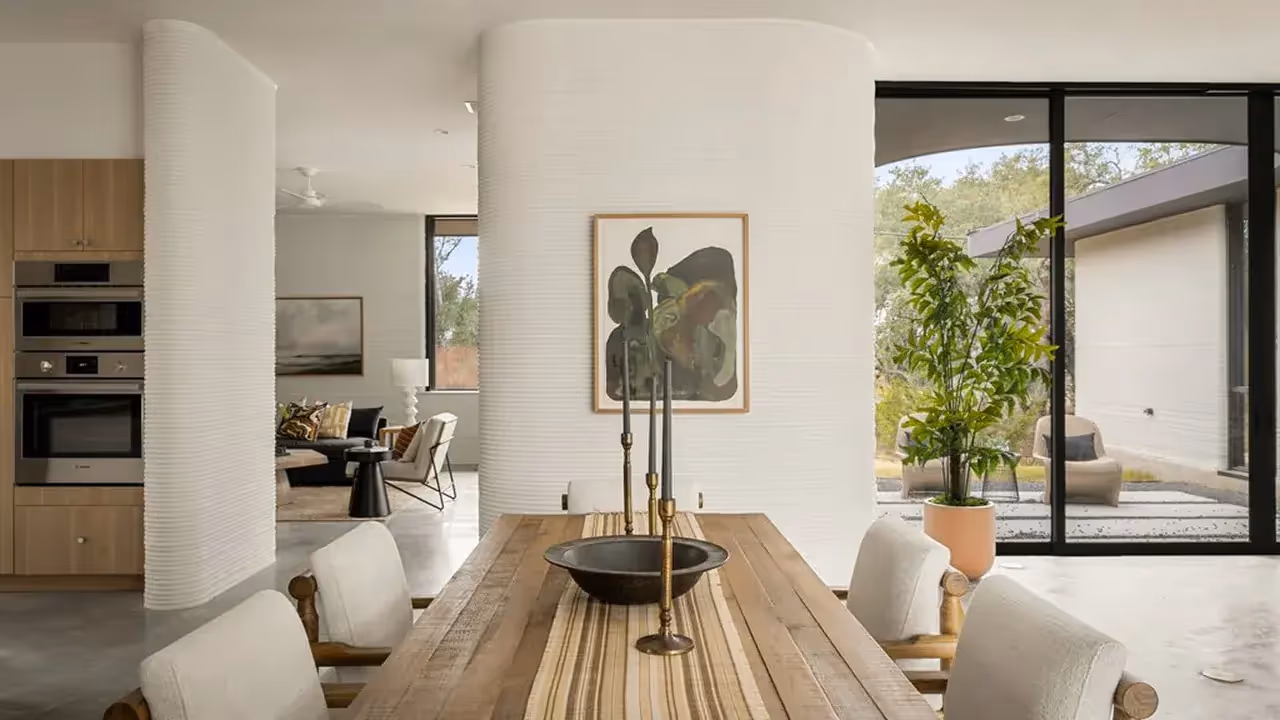 Wooden dining table with brass candlesticks, ribbed curved white interior column and glass doors